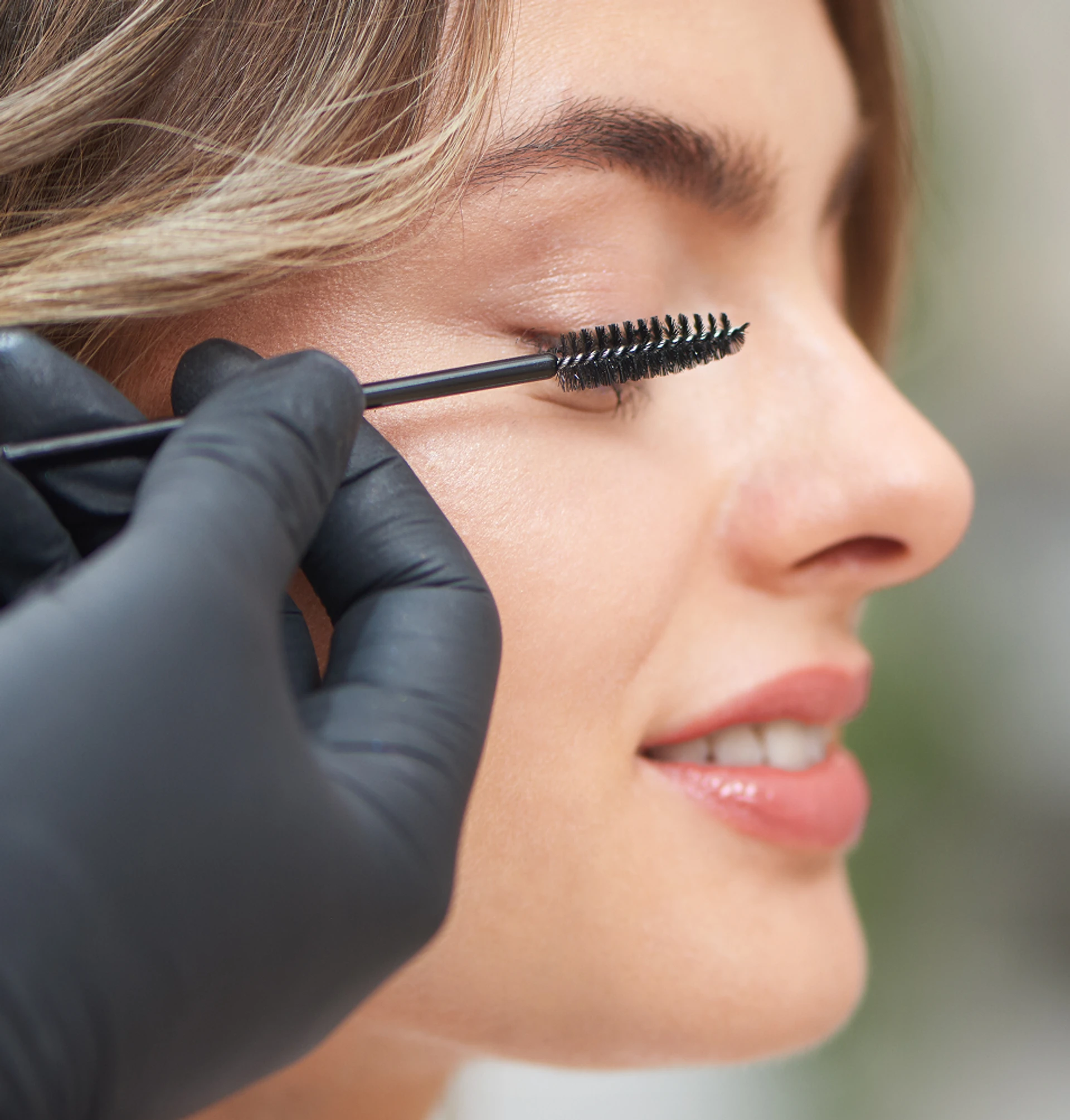 femme brossant les cils de sa cliente femme brossant les cils de sa cliente